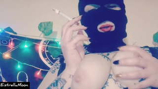 Whore with mask touches her large breasts while smoking