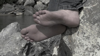 Feet of a older woman on the river bank.